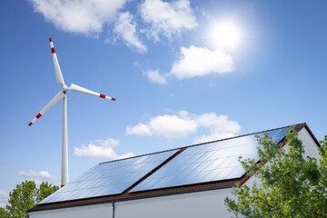Solar panels on a roof and a wind turbine for renewable energy generation © photoschmidt