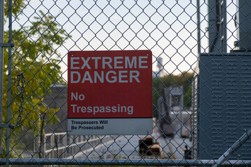 Old weathered sign extreme danger no trespassing trespassers will be prosecuted on wire fence at...