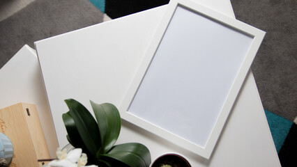 Blank photo frame to place text or image, on white wooden background with flowers around