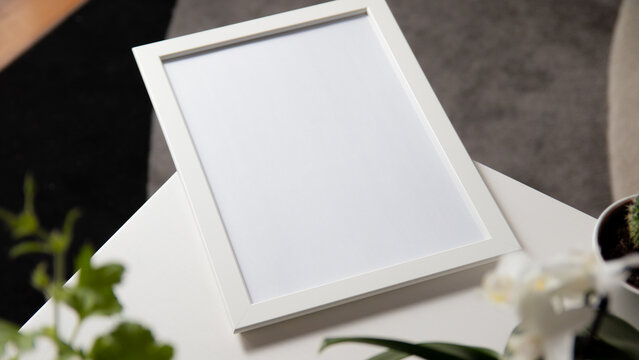 Blank photo frame to place text or image, on white wooden background with flowers around