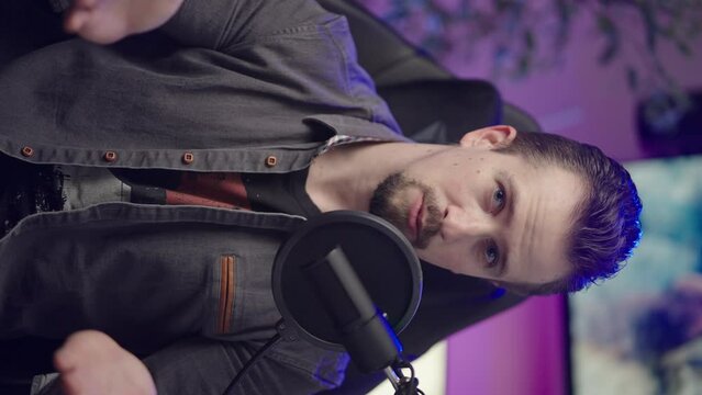 Male person influencer on gaming chair talking to camera vertical video 4K