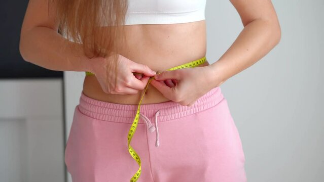 Women's health, female measuring her slim waist after weight loss