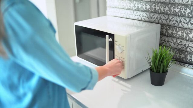 Woman warming up food in the microwave oven