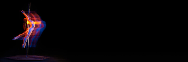 Young girl performing pole dance isolated over black studio background with mixed neon lights....