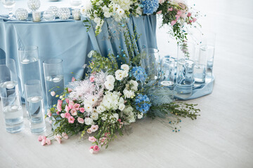Wedding ceremony. Presidium for the newlyweds, decorated with candles and vases with blue and pink natural flowers such as eustoma, hydrangea, roses. Floristic concept