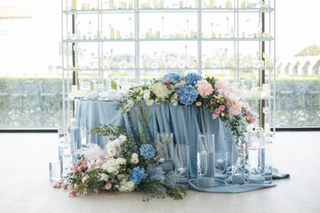 Wedding ceremony. Presidium for the newlyweds, decorated with candles and vases with blue and pink natural flowers such as eustoma, hydrangea, roses. Floristic concept