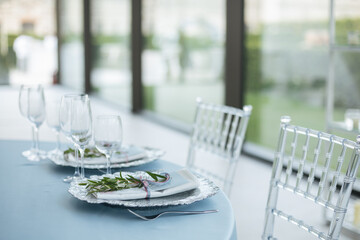 Served wedding table with decorative flowers and transparent chairs. Celebration details. 