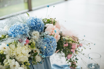 Wedding ceremony. Presidium for the newlyweds, decorated with candles and vases with blue and pink natural flowers such as eustoma, hydrangea, roses. Floristic concept