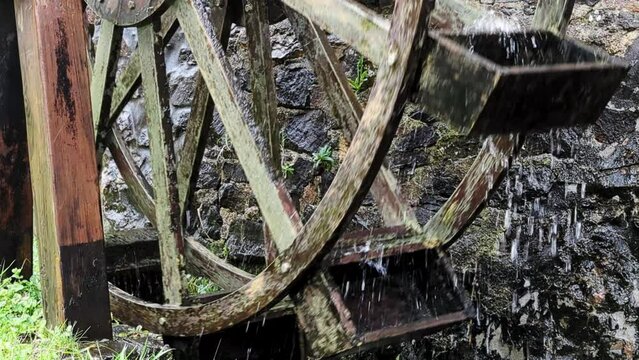 Water wooden mill with splashes of water on the background of a stone wall. Close-up.