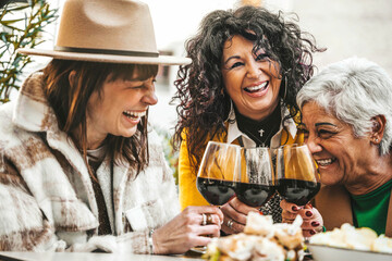 Happy senior women drinking red wine at bar restaurant - Mature people having fun hanging out on city street - Life style concept with older friends smiling and laughing together