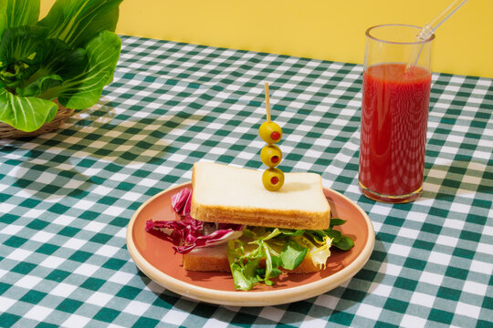 Delicious smoothie and healthy sandwich on checkered tablecloth