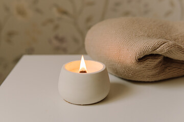 Interior candle in a plaster candlestick. Natural. Handmade candle and knitted sweater. Soft focus....