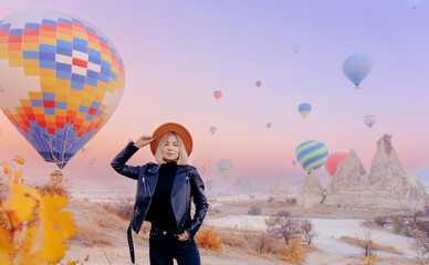 Happy young woman tourist in hat with hot air balloons in Cappadocia Turkey - obrazy, fototapety, plakaty
