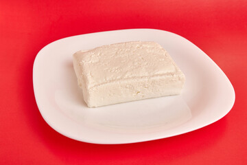 A slice of sour milk cheese on a white plate.