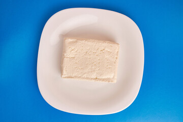 A slice of sour milk cheese on a white plate.