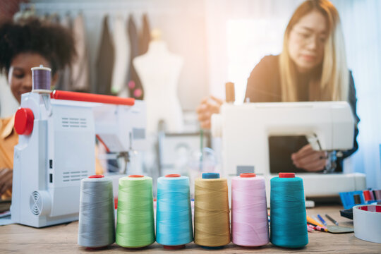 Close Up Roll Of Thread Background Is Fashion Designer Working In Clothes In Tailoring Atelier. Tailor Woman With Fabric And Clothing Sketches At The Office.