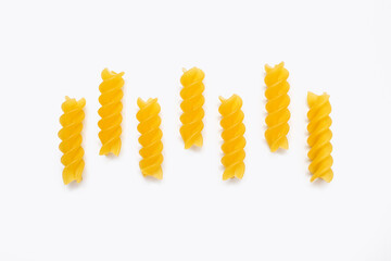 Dry pasta in the form of spirals on a white isolated background. Twisted pasta laid out in a row. Italian cuisine in the form of durum wheat pasta. Delicious national dish
