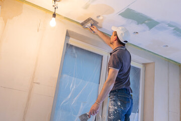 Obraz na płótnie Canvas Worker make repairs in new apartment. Man plaster walls and ceilings. High quality photo