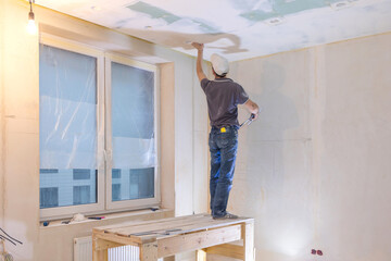Fototapeta premium Worker make repairs in new apartment. Man plaster walls and ceilings. High quality photo