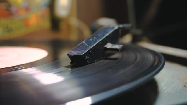 Hand turns on a vintage vinyl record. The needle rises from a vintage vinyl record. The vinyl record is spinning. The needle plays on a vintage vinyl record. Old turntable.