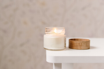 Handmade candle in a glass with wooden lid in bedroom. Natural. Space for text. Soft focus. Scented candle for home
