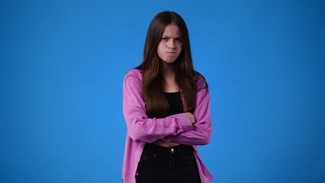 4k video of one girl with a negative expression and crossed arms over blue background.