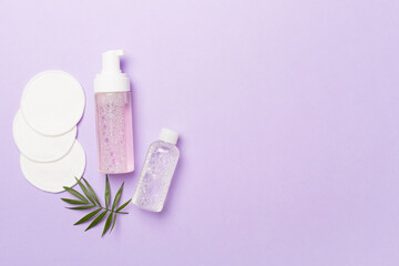 Obraz na płótnie Canvas Foaming facial cleanser and micellar water with eco pads on color background, top view