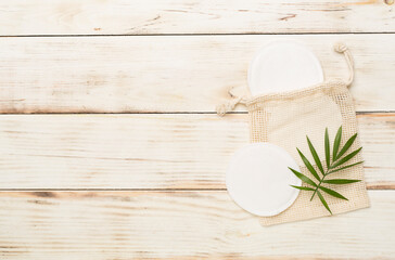 Eco cotton pads with sack on wooden background, top view