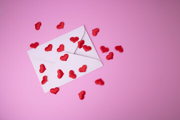 White envelope with red hearts for Valentine's Day on a pink background. The concept of a love message for March 8, Mother's Day, Father's Day, family Day.