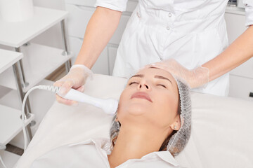 Beautician makes RF lifting for rejuvenation woman face, anti aging cosmetic procedure in beauty...