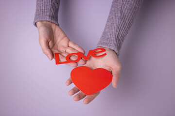 Hands stretch out a red heart and the word love