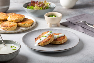 Greek zucchini fritters Kolokithokeftedes on gray background. Zucchini pancakes with feta and herbs, served with greek yogurt.