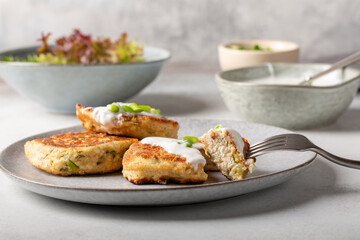 Greek zucchini fritters Kolokithokeftedes on gray background. Zucchini pancakes with feta and herbs, served with greek yogurt.