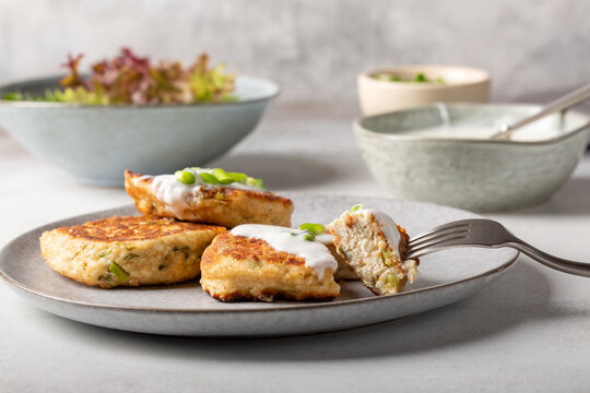 Greek zucchini fritters Kolokithokeftedes on gray background. Zucchini pancakes with feta and herbs, served with greek yogurt.