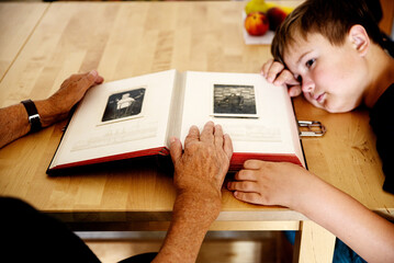 grandparents and grandchild look at an old album with family photos

