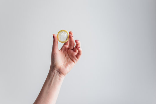 Una mujer sostiene un preservativo masculino sin envoltorio sobre fondo blanco. Sexo seguro. Protecci&oacute;n contra embarazos y enfermedades de transmisi&oacute;n sexual. M&eacute;todos anticonceptivos