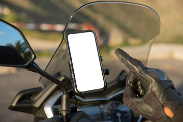 Close-up of a biker's hand pointing at the blank screen with mockup of his smartphone mounted on...