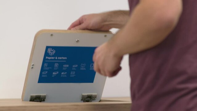 Un employ&eacute; dans une entreprise jette du papier dans une poubelle de tri pour le recycler