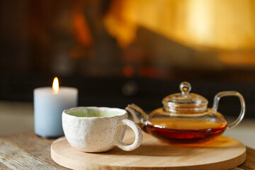 Obraz na płótnie Canvas Glas teapot on the table in room with fireplace cozy autumn still life.