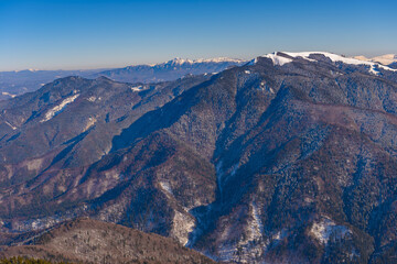 Fototapeta na wymiar Panorama of the Piatra Mare massif, Brasov, Romania, Prahova Valley below, and the Ciucas Mountains in the background. Beautiful alpine winter panoramic view, snow capped mountains in background