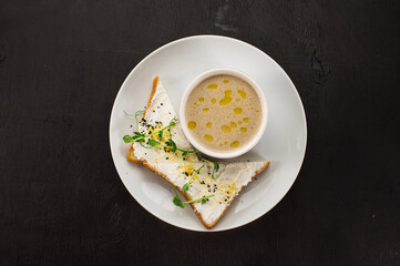 Tasty mushroom cream soup with a sandwich on black wooden background