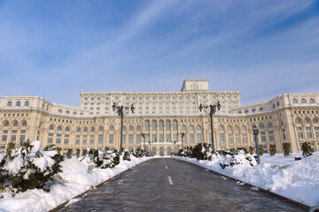 Fototapeta na wymiar Large building of the Palace of the Parliament also known as People's House (Casa Poporului) in Constitutiei Square (Piata Constitutiei) in Bucharest, Romania, East Europe, in snowy winter scenery
