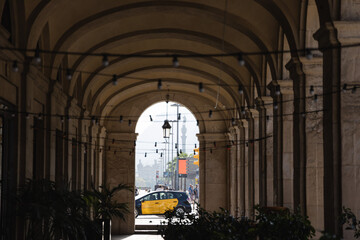 View of yellow taxi of Barcelona through the arcades in Passeig Colom, corridor architecture of...