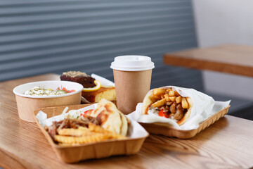 Greek fast food dinner served in recyclable dishware on table. Souvlaki, gyros, fries and salad in disposable plates