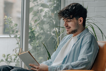young man reading a textbook at home