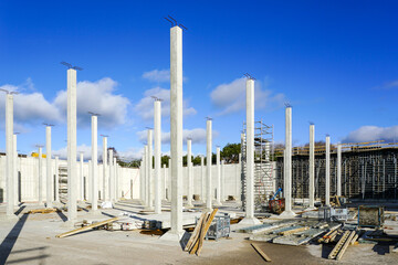 Many white vertical reinforced concrete columns at the construction site of an industrial facility