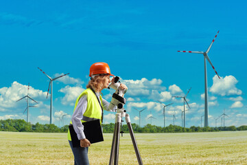 emale geodetic surveyor working with a measuring device on a wind farm