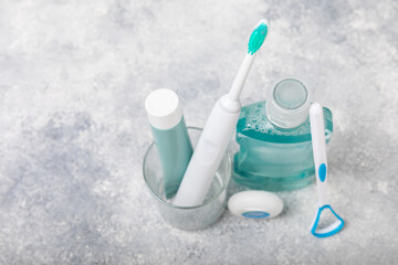 Electronic ultrasonic toothbrush, mouthwash, floss, tongue cleaner and toothpaste on blue textured...