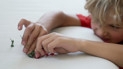 Close up of child hands playing with miniature figurines. One Imaginative small kid plays with toy...