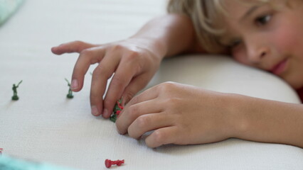 Close up of child hands playing with miniature figurines. One Imaginative small kid plays with toy soldiers by himself
